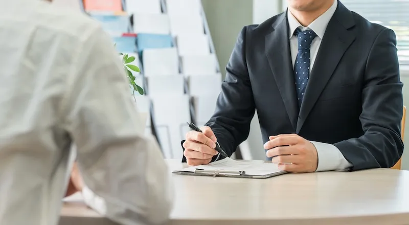 スーツ姿の担当者が書類を前に商談する様子